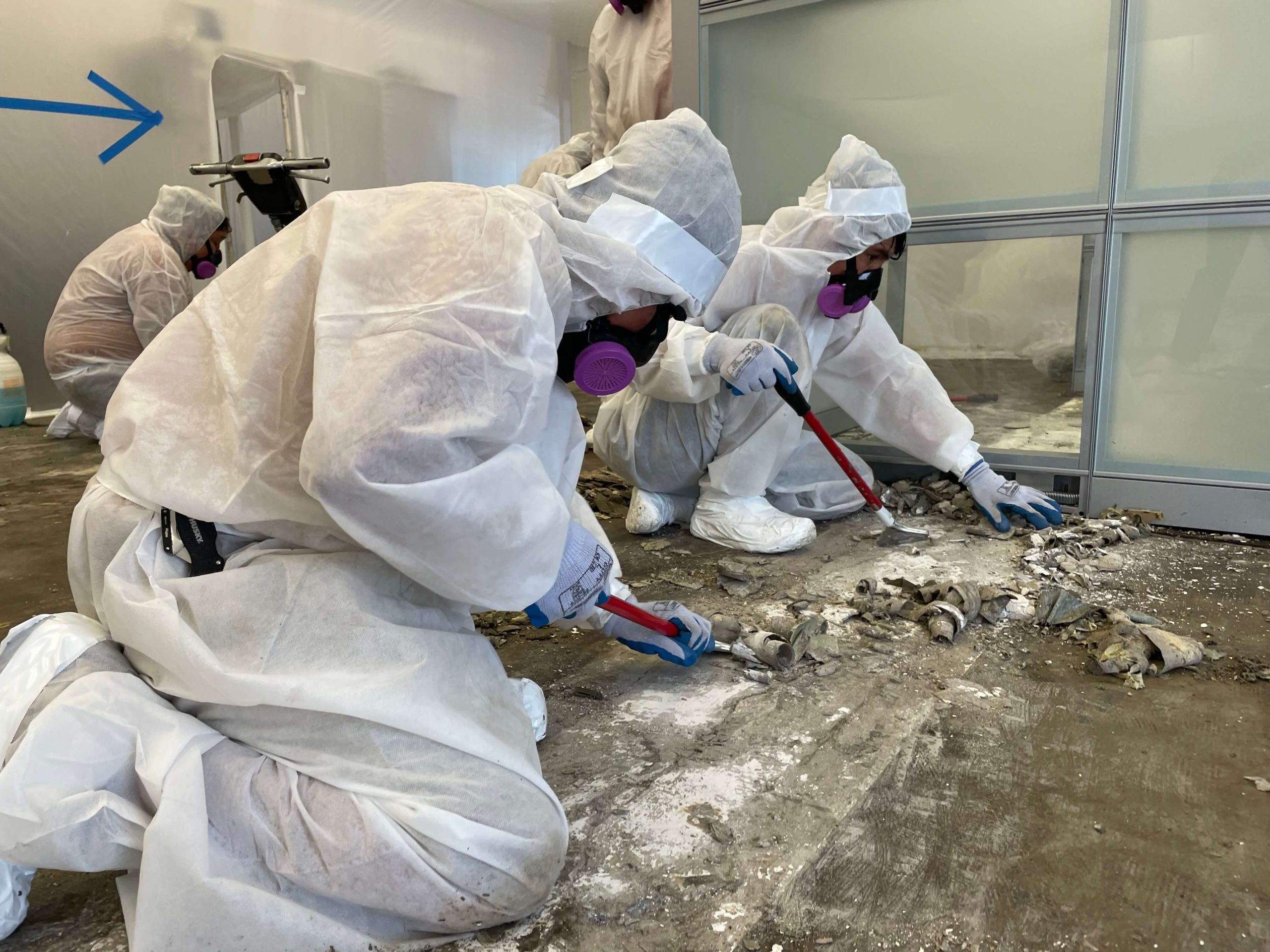 Workers wearing protective gear while they strip the flooring