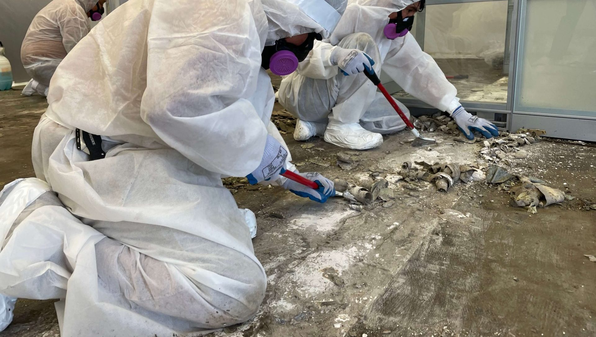 Workers wearing protective gear while they strip the flooring