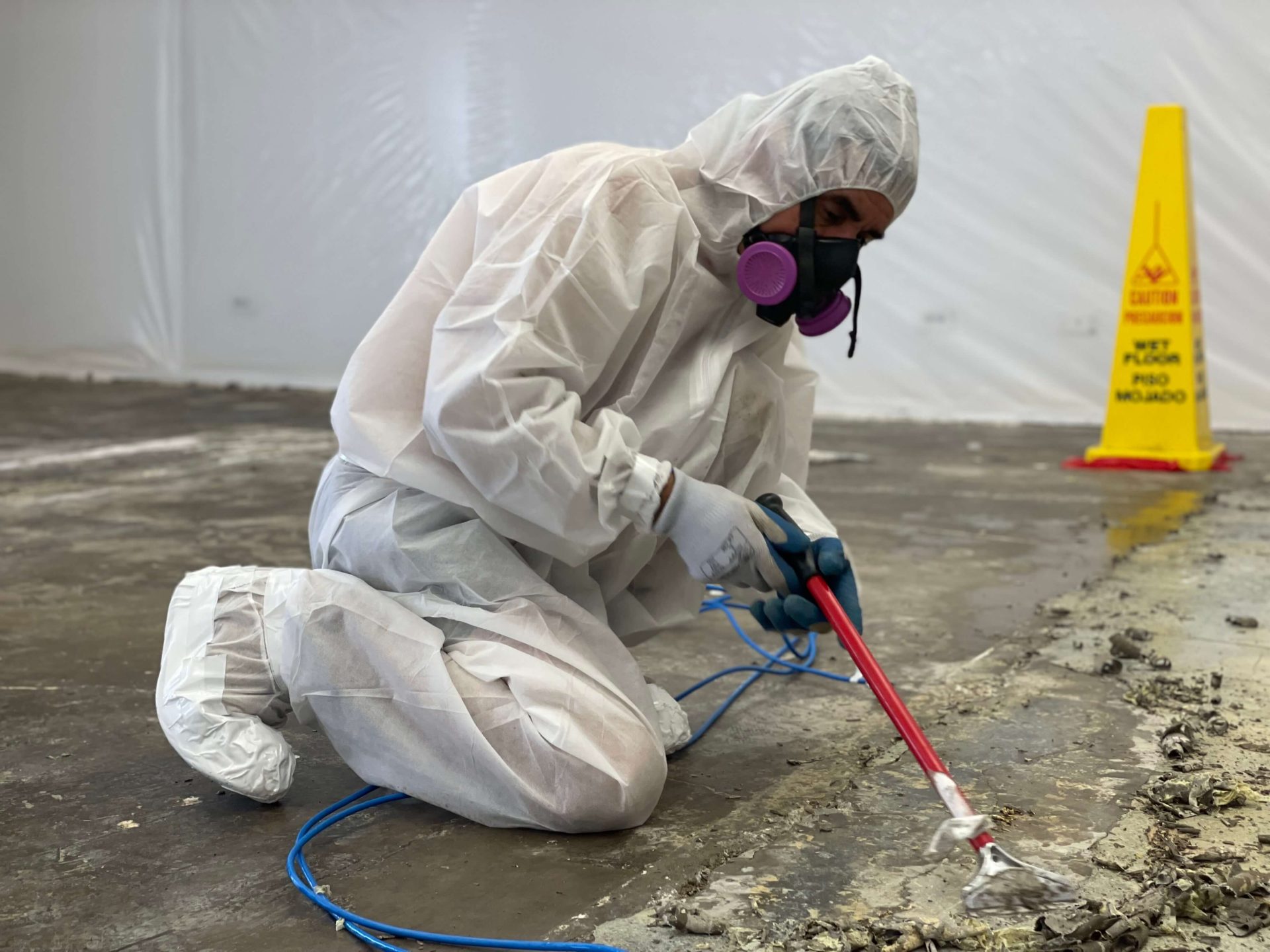 Workers wearing protective gear while they strip the flooring