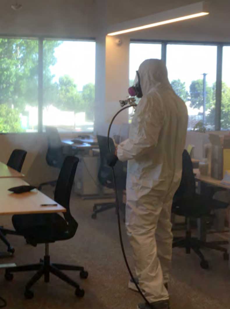 biohazard_3 Disinfection specialist in protective suit sanitizing office workspace with spray equipment during professional decontamination service.